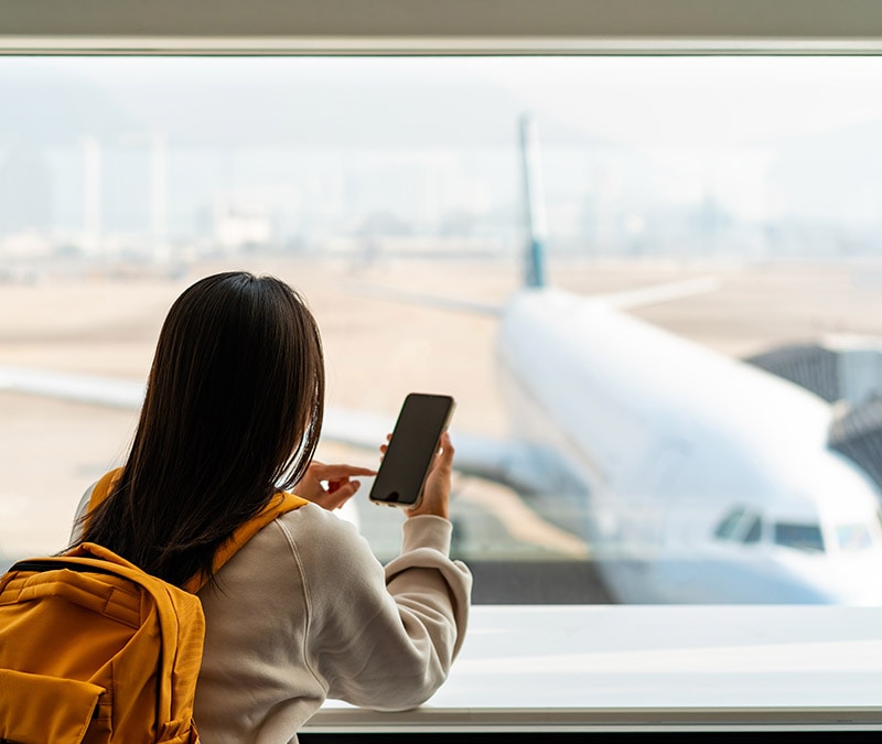 Photo d'une femme utilisant un VPN pour accéder en toute sécurité au réseau Wi-Fi public d'un aéroport.