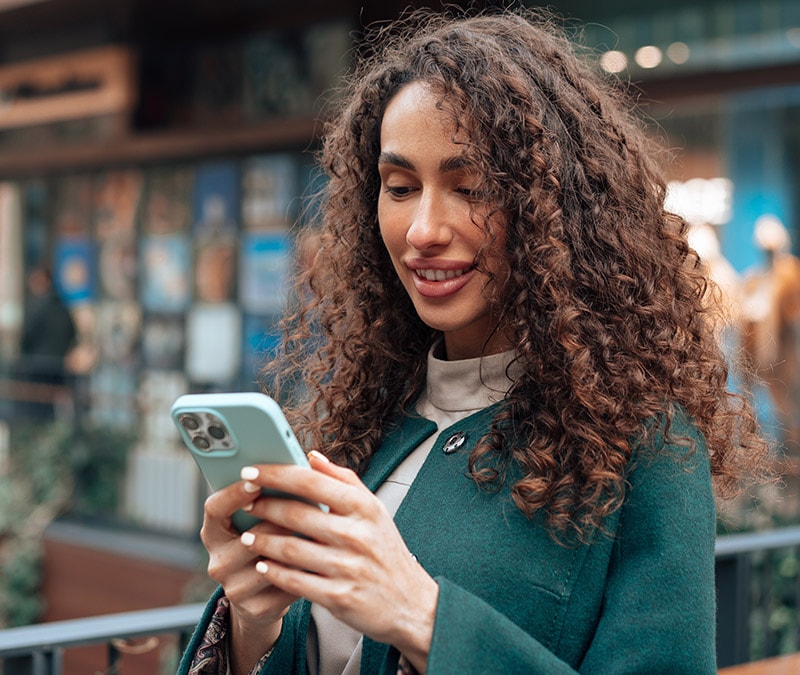 Une femme aux cheveux bouclés vérifie que son iPhone ne contient pas de virus. 