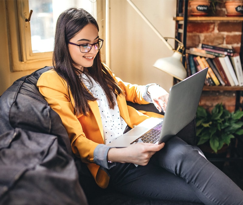 Une image d'une femme assise devant son ordinateur portable et vérifiant si elle a reçu un faux message de virus.