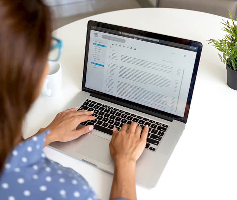 Une personne consultant ses e-mails, qui contiennent potentiellement des arnaques au support technique.