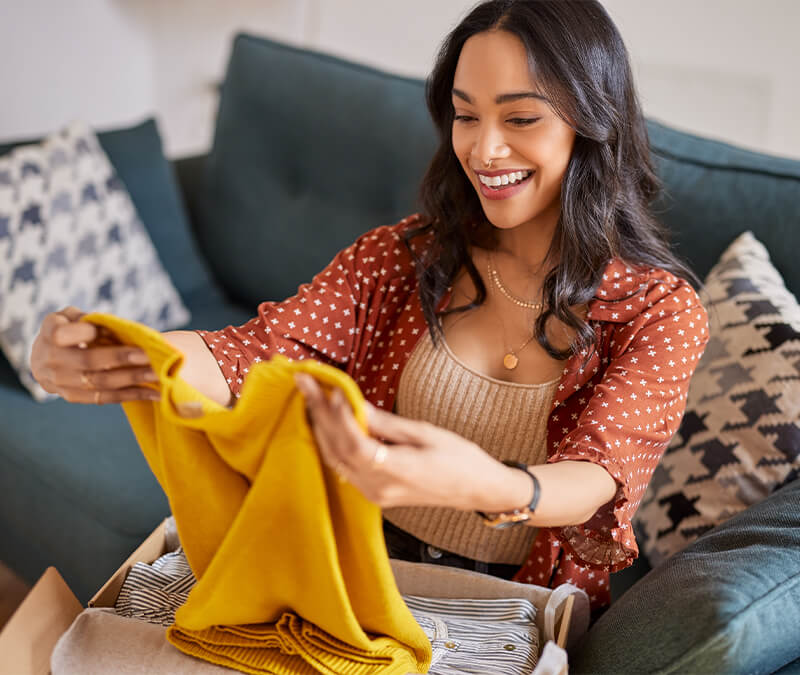 Une femme souriante regardant un pull jaune sur Temu, suggérant que Temu est fiable. L'est-il vraiment ?