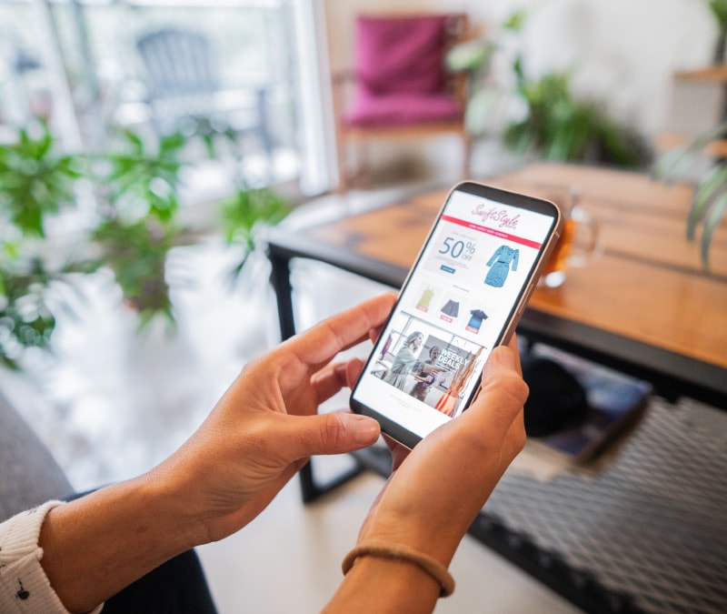 Une image de mains tenant un smartphone avec une publicité malveillante potentielle dessus.