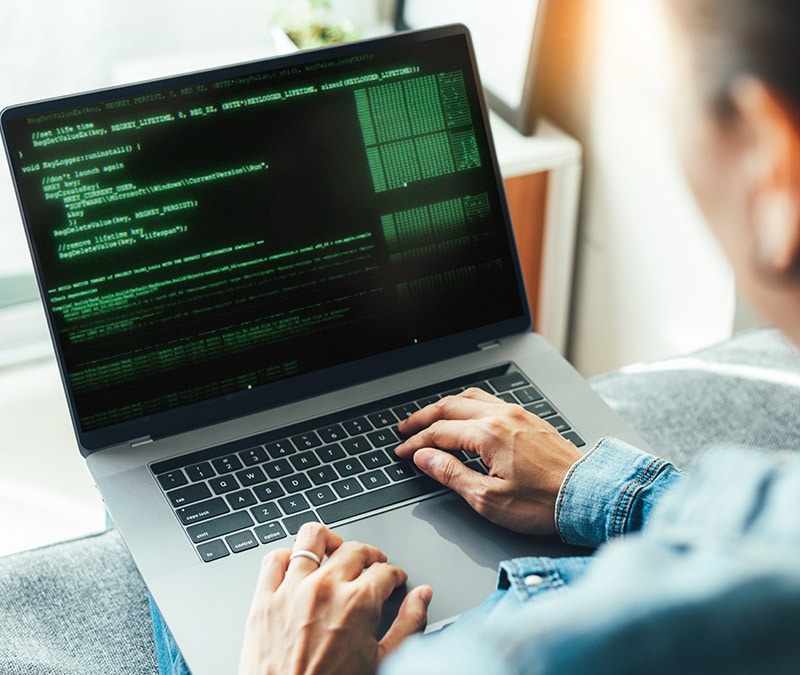 Homme regardant son ordinateur alors qu'il s'informe sur les malwares.