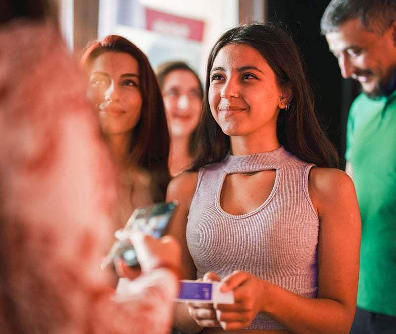 Une femme heureuse faisant la queue pour un concert quelques instants avant de découvrir qu'elle a été victime d'une escroquerie sur Ticketmaster.