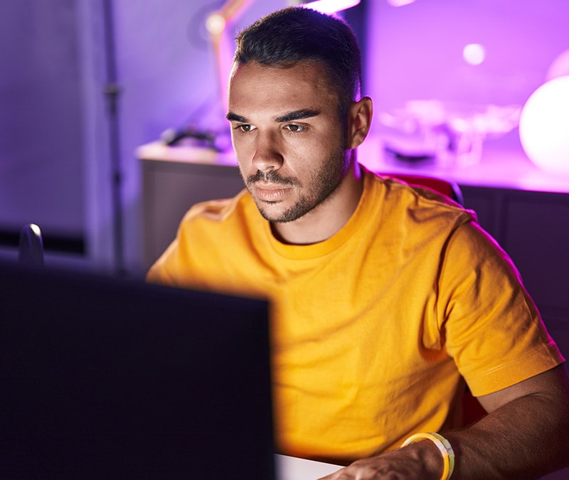 Un homme est assis devant un ordinateur portable et fait des recherches sur le navigateur Tor et sur la manière dont il est utilisé pour accéder au Dark Web.