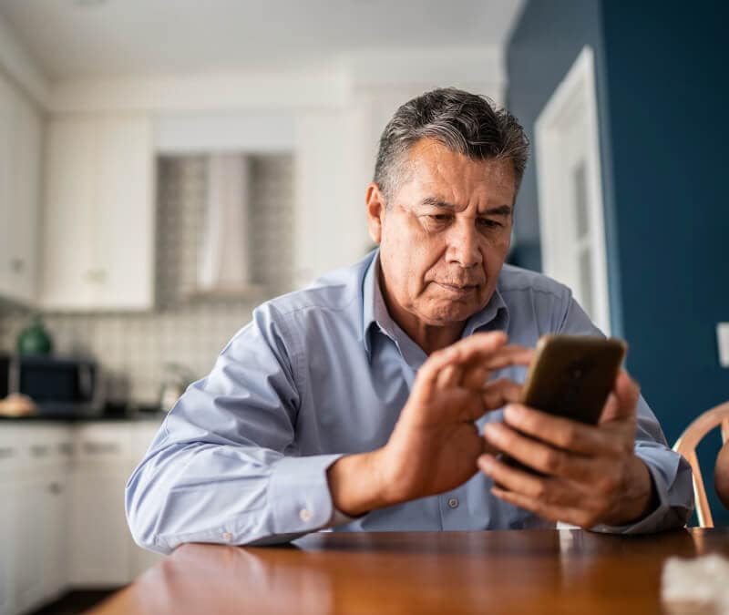 Un homme compose un numéro sur son smartphone pour vérifier si son téléphone est piraté.