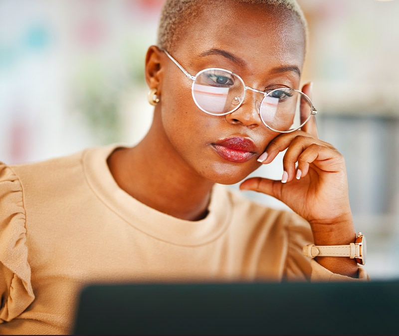 Une femme regarde son ordinateur portable, réfléchissant à ce qu'elle doit faire lorsqu'un escroc a son adresse e-mail.