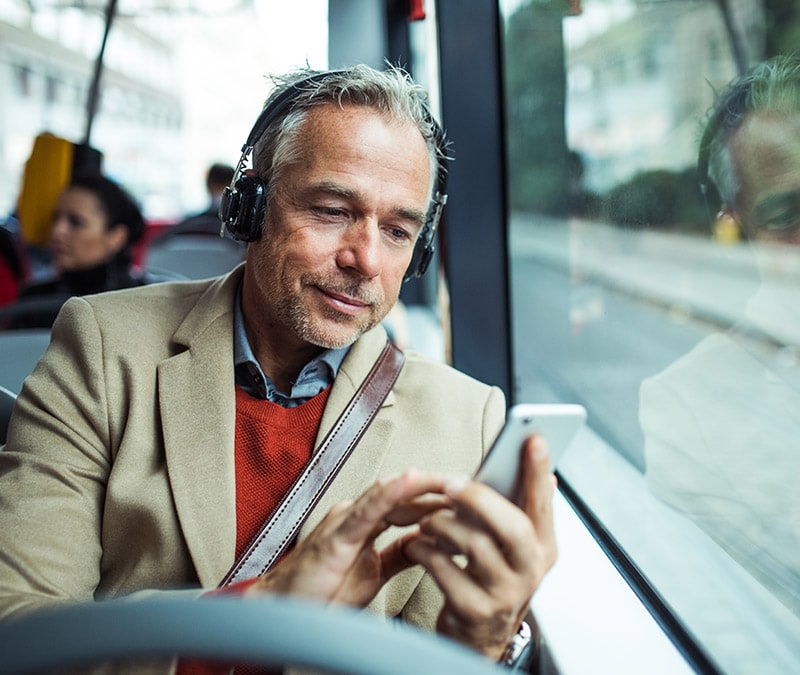 Un homme assis dans un bus regarde son smartphone en se demandant pourquoi il est si lent.