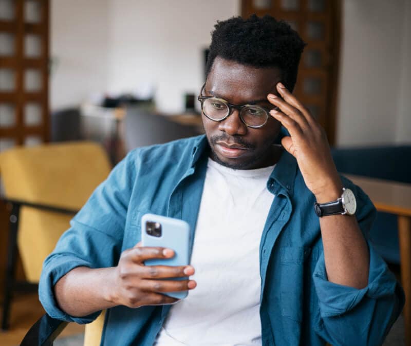 Un homme regarde son téléphone et se demande : « Les iPhone peuvent-ils être piratés ? »