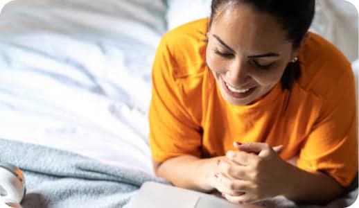 Femme sur un lit avec un ordinateur portable.