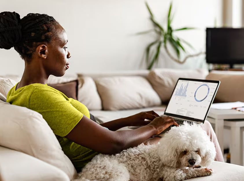 Femme assise avec un chien travaillant sur un ordinateur portable